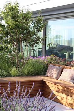 a wooden bench sitting in the middle of a garden filled with purple flowers and plants