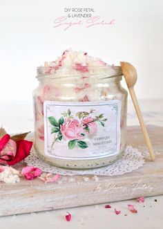 a jar filled with pink flowers next to a wooden spoon