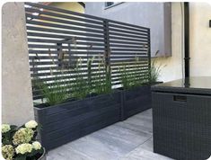 an outdoor patio with black planters and plants on the side of the building,