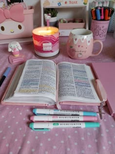 a pink table topped with an open book and lots of writing supplies on top of it