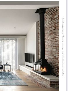 a living room filled with furniture and a fire place next to a brick wall covered in curtains