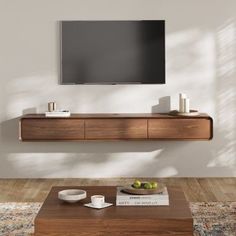 a flat screen tv mounted to the side of a wall above a wooden coffee table