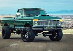 a green pickup truck parked on top of a hill