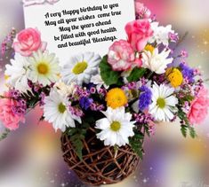 a basket filled with lots of flowers next to a sign that says happy birthday to you