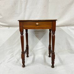 a small wooden table with one drawer on the top and two legs at the bottom