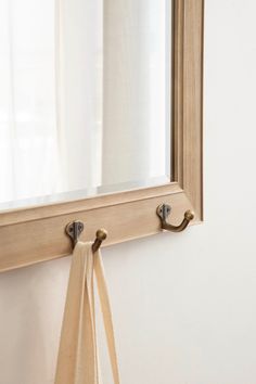 a mirror hanging on the side of a wall next to a tie rack and window