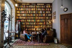 two people sitting at a table in front of a bookshelf full of books