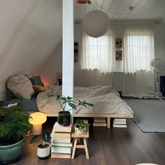 a bed room with a neatly made bed and lots of plants on the floor next to it