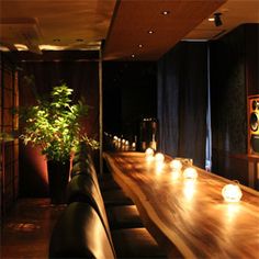 a long table with candles on it in a dimly lit room next to a potted plant