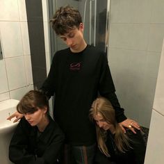 three young people standing in front of a bathroom sink with their hands on the floor