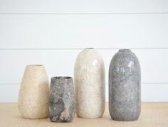 three vases sitting next to each other on top of a wooden table in front of a white wall