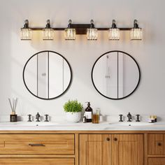 two round mirrors on the wall above double sinks in a bathroom with wood cabinets and white walls