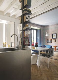 an open kitchen and dining room area with wood flooring, white walls and wooden beams