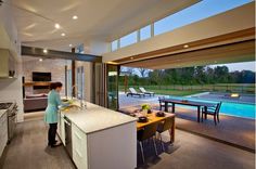 a woman standing in a kitchen next to a pool