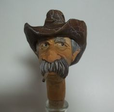 an old man's head with a pipe in his mouth and a hat on top