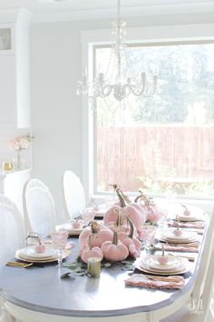 a dining room table is set with pink pumpkins