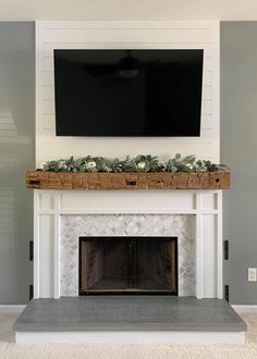 a fireplace with a flat screen tv mounted above it and some plants on the mantle