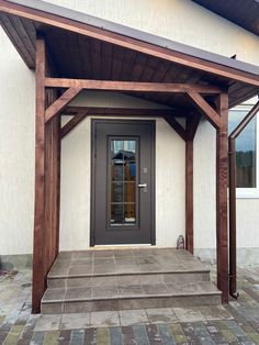 the front entrance to a house with a wooden porch and pergolated walkway leading up to it