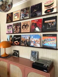 there are many records hanging on the wall next to a lamp and record player in front of it