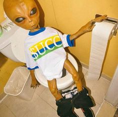 an alien sitting on top of a toilet in a bathroom next to a roll of toilet paper