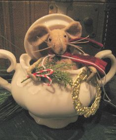 a mouse sitting in a tea pot with christmas decorations on the rim around its neck