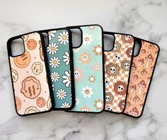 four phone cases sitting next to each other on a marble counter top with flowers and skulls