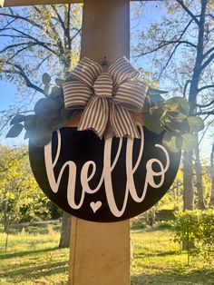 a black and white door hanger with the word hello written on it in front of trees