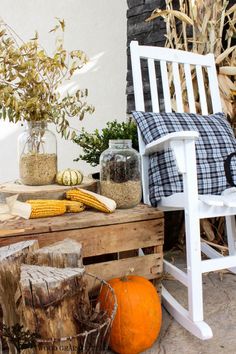 a white rocking chair sitting on top of a wooden table next to a corn cob