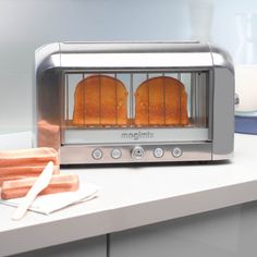 two toasters with hot dogs in them sitting on a counter next to some milk