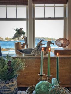 two birds sitting on top of a window sill next to candles and vases