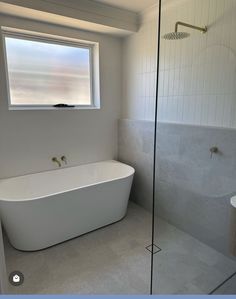 a white bath tub sitting under a bathroom window