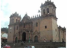 an old church with stairs leading up to it and cars parked in the street below