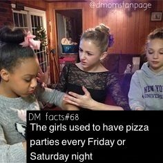 two girls are helping another girl put toppings on a pizza crust in the kitchen