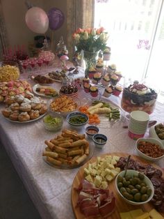 a table filled with lots of food on top of a white table covered in balloons