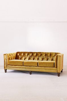 a gold colored leather couch sitting on top of a white floor