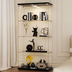 a book shelf filled with books and figurines on top of each other next to a bed