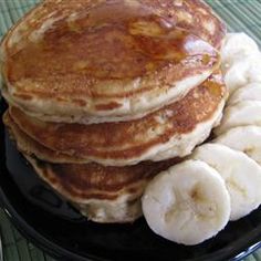 pancakes with bananas and syrup on a black plate