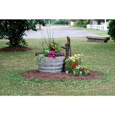 a wooden barrel filled with flowers next to a bench