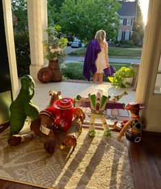 a woman standing in front of an open door with stuffed animals on the floor next to her