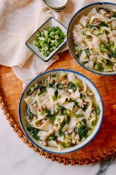 two bowls filled with noodles and vegetables on a table