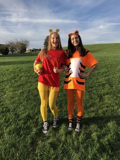 two girls dressed as winnie the pooh and tigger are standing in a field