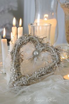 a heart shaped candle holder sitting on top of a table next to some lit candles