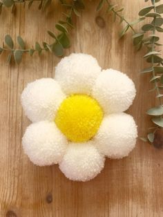 a white and yellow flower sitting on top of a wooden table