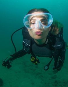 a woman scubas in the water with goggles on