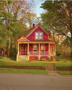 a red and white house sitting on the side of a road in front of trees