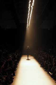 a person walking down a runway in front of a large group of people at night