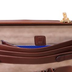 a brown and tan briefcase with blue accents on the inside pocket, sitting upright in front of a white background