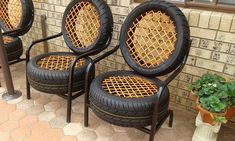 four black chairs sitting next to each other in front of a brick wall and potted plant