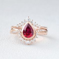 a close up of a ring with a red stone in the center and white diamonds around it