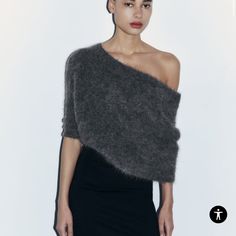 a woman in a grey sweater and black skirt